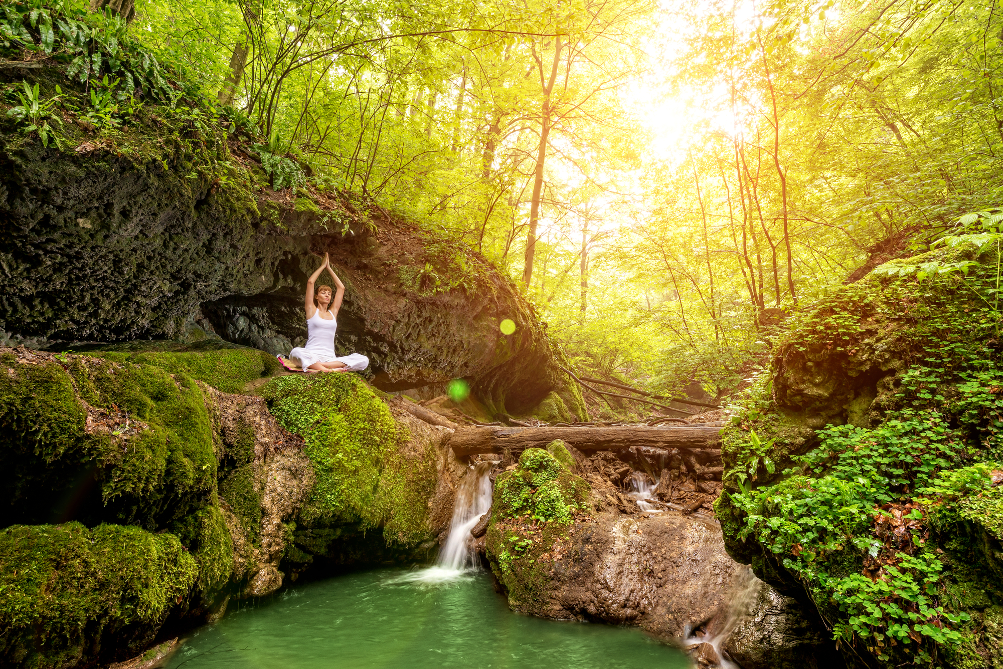 Woman practices yoga at the waterfall. Sukhasana pose